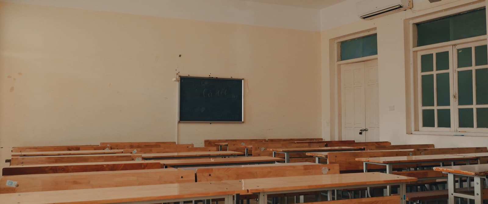 An empty classroom with wooden desks and a chalkboard — the kind of learning environment Founder's Point supports with parent communication and billing automation.